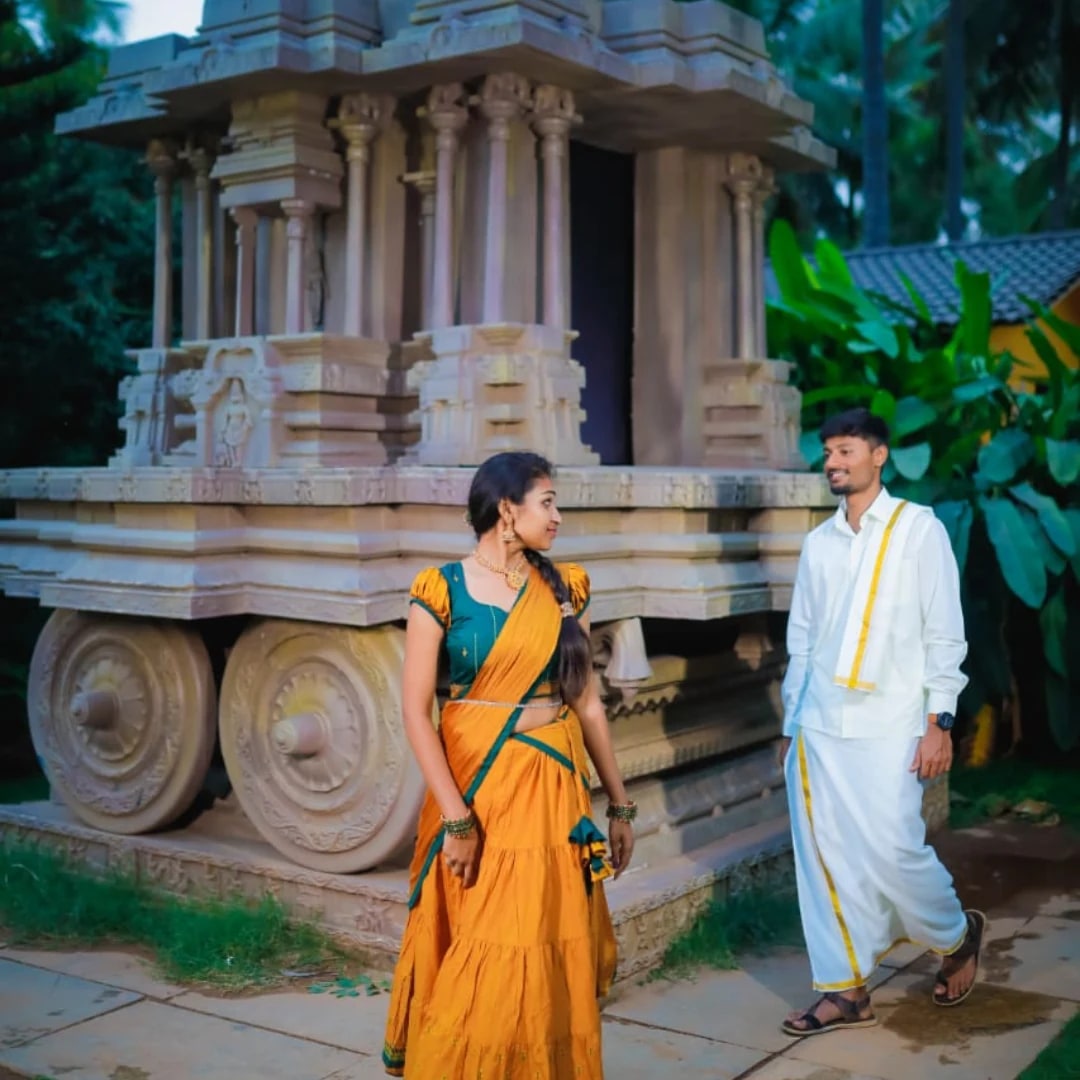 A pre-wedding photograph of a couple beside a stone chariot